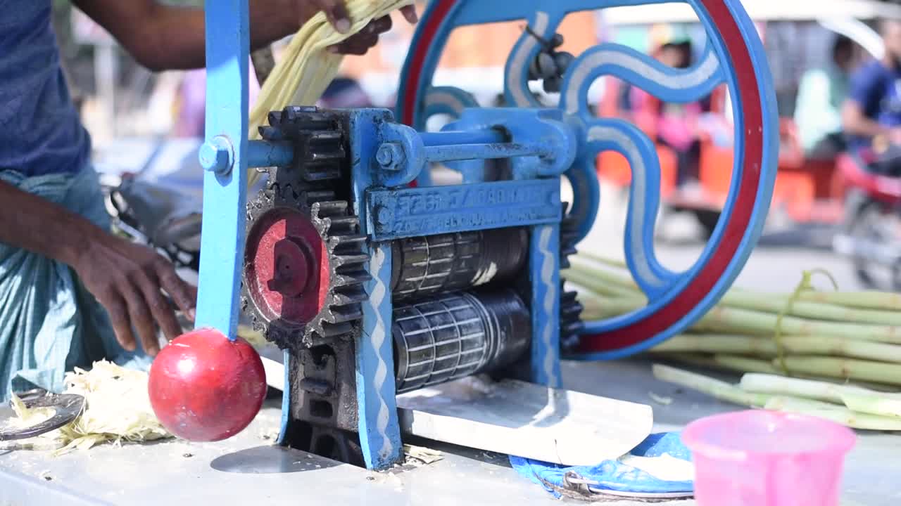 Street vendor using manual machine to take out Sugarcane juice for customers