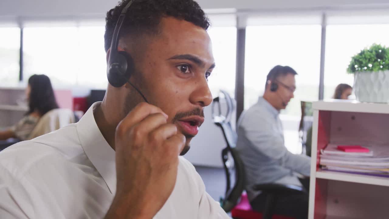Professional businessman smiling while talking on phone headset in modern office in slow motion