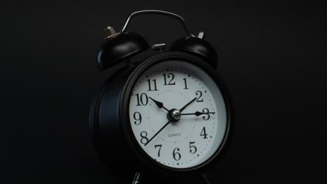 ticking black twin bell alarm clock, zoom dolly in shot, time passing concept