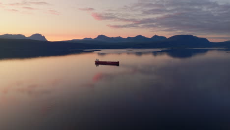buque portacontenedores anclado en la tranquila bahía noruega, vista aérea del arco de la hora dorada