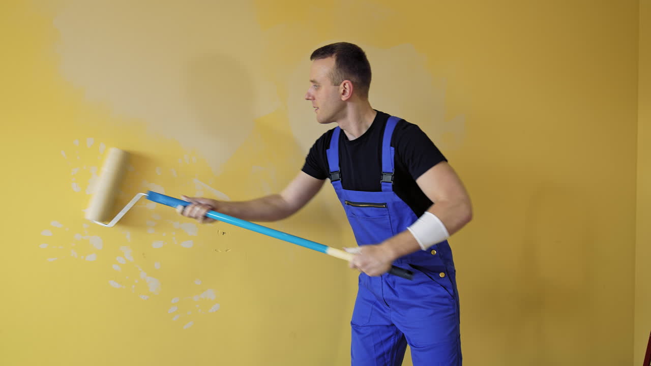 Man painting wall at home. Portrait view of painter hands painting the wall
