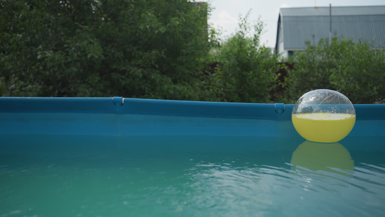 Sunlit Peaceful Reflection, Serene Backyard Setting With Floating Yellow Ball And Gentle Ripples, Peaceful Pool Scene Featuring Yellow Ball Amid Calm Water And Mirrorlike Reflections