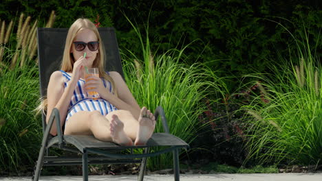 teenage girl relaxing on a sun lounger by the pool, drinking a cocktail