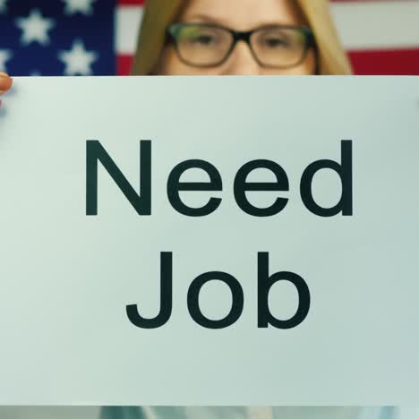 woman holding a poster that states need job