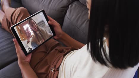 Mujer-Afroamericana-Haciendo-Una-Videollamada-En-Una-Tableta-Digital-Sentada-En-El-Sofá-De-Casa