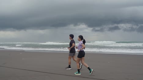 couple running on a beach on a cloudy day