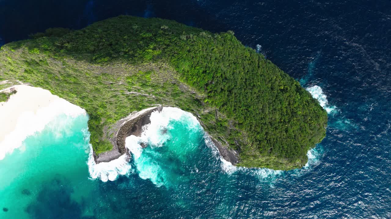 Iconic Kelingking beach and cliff surrounded by blue ocean, aerial top-down view
