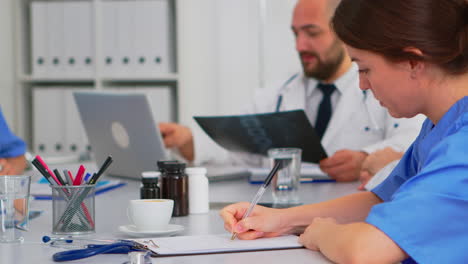 nurse taking notes on clipboard while radiologist coworkers discussing