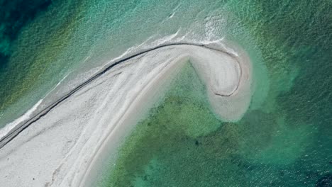 beautiful drone shot of sandbank like a comma in green gradient sea, amorgos, cyclades island in greece