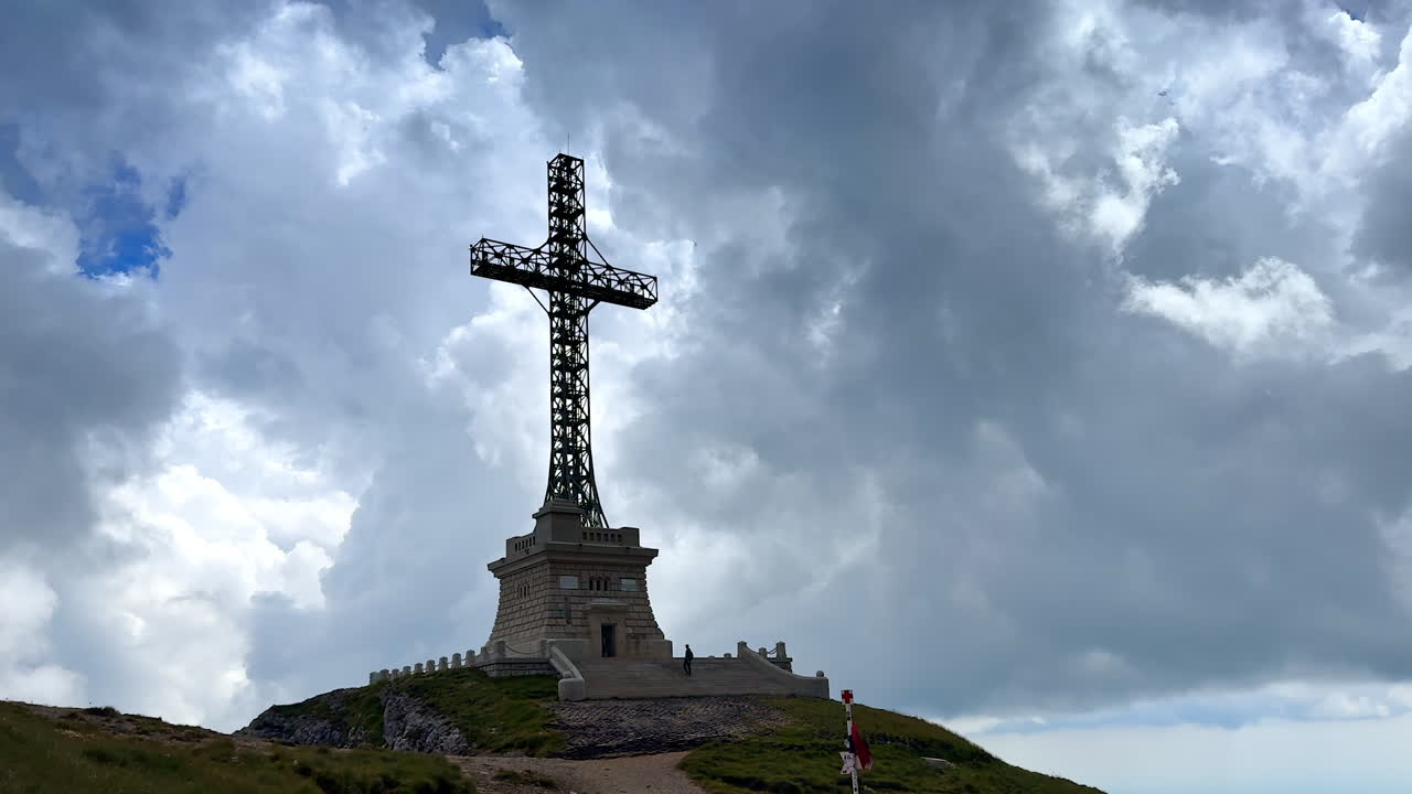 The Heroes' Cross close to the Caraiman peak in the Bucegi Mountains, Romania. Low angle view. Dramatic cloudscape covers the sky at backdrop