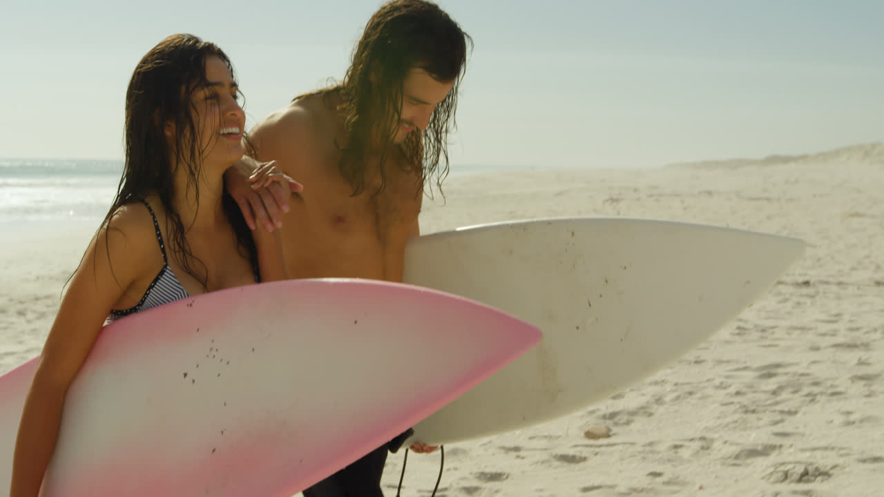 pareja con tabla de surf caminando por la playa 4k 4k