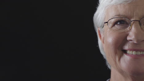 half-face-portrait-of-happy-elderly-woman-laughing-looking-at-camera-cheerful-wearing-glasses-on-black-background-isolated