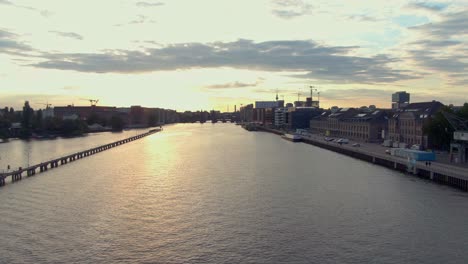 Berliner-Stadtbild-Luftdrohnenaufnahme,-Die-Bei-Sonnenuntergang-Tief-über-Die-Spree-In-Richtung-Oberbaumbrücke-Fliegt