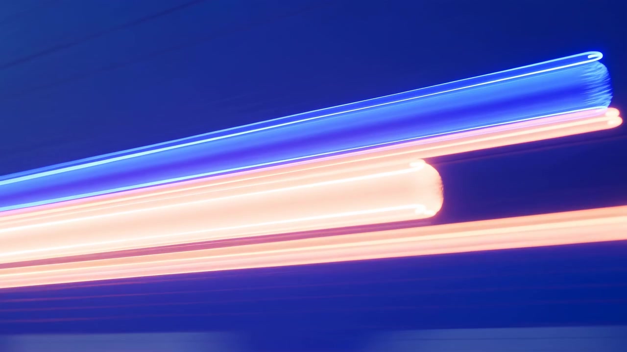 Vista obliqua ravvicinata di luci tubolari illuminate che si incrociano diagonalmente, mostrando nuclei luminosi bianco-blu e bianco-rosa caldo, bordi lucidi e brillanti, riflessi tenui, contrasto vivido, movimento astratto elegante.