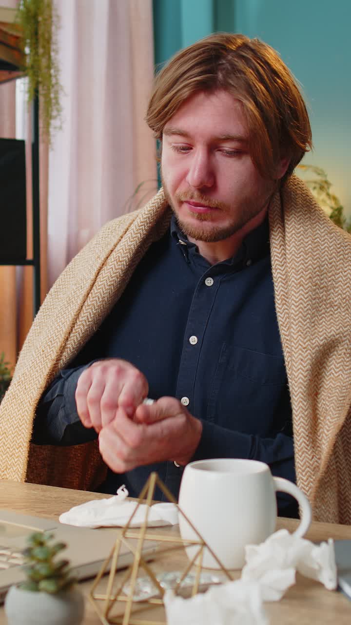 Sick ill young businessman suffering from cold flu or allergy wipes snot working on laptop at office