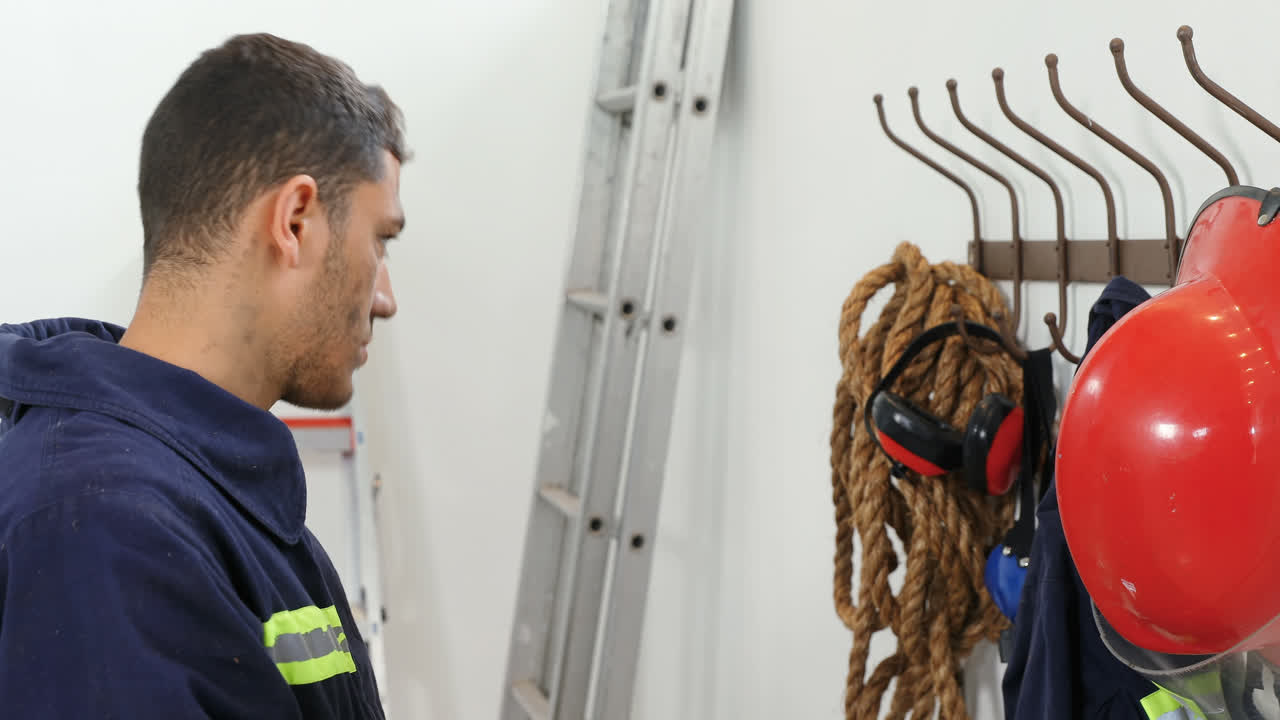 bombero poniendo el casco de seguridad en el gancho 4k