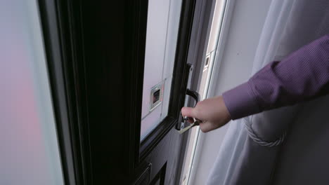 Male-hand-closes,-locks-and-checks-front-door-from-hallway-inside-house