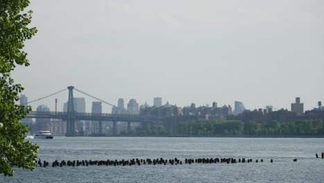 Un-Catamarán-De-Un-Crucero-Fluvial-Avanza,-Deslizándose-Más-Allá-Del-Icónico-Puente-De-Brooklyn-En-El-Río-Este-De-Nueva-York