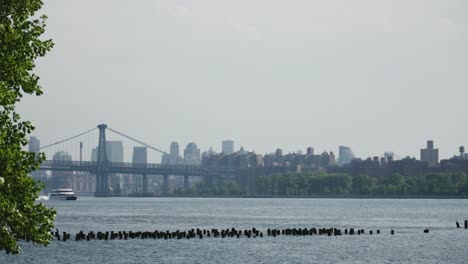 un catamarán de crucero fluvial avanza, deslizándose más allá del icónico puente de brooklyn en el east river de nueva york