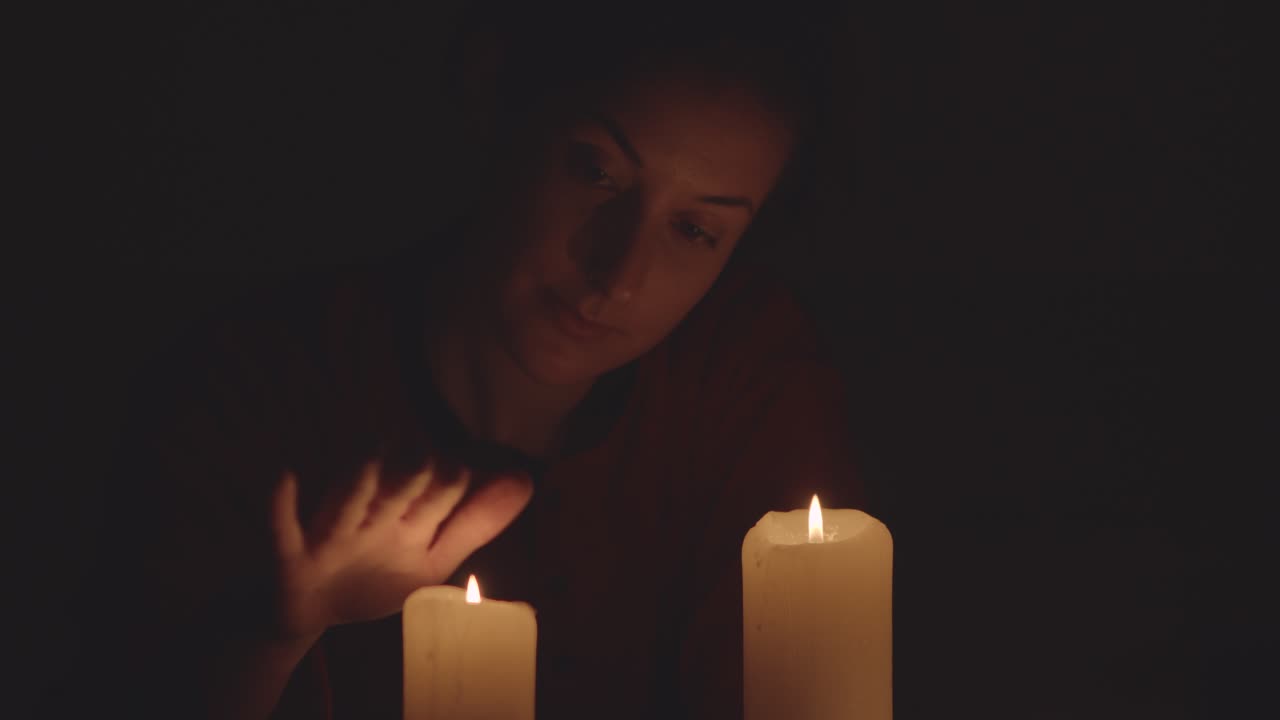 mujer y velas en la oscuridad