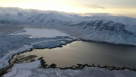 an aerial view shows snowcovered mountains circling a lake in iceland