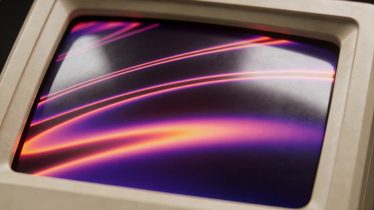 Mostrando un monitor CRT beige con un'animazione che inizia, strisce rosa che si muovono su una scrivania con un bagliore bianco