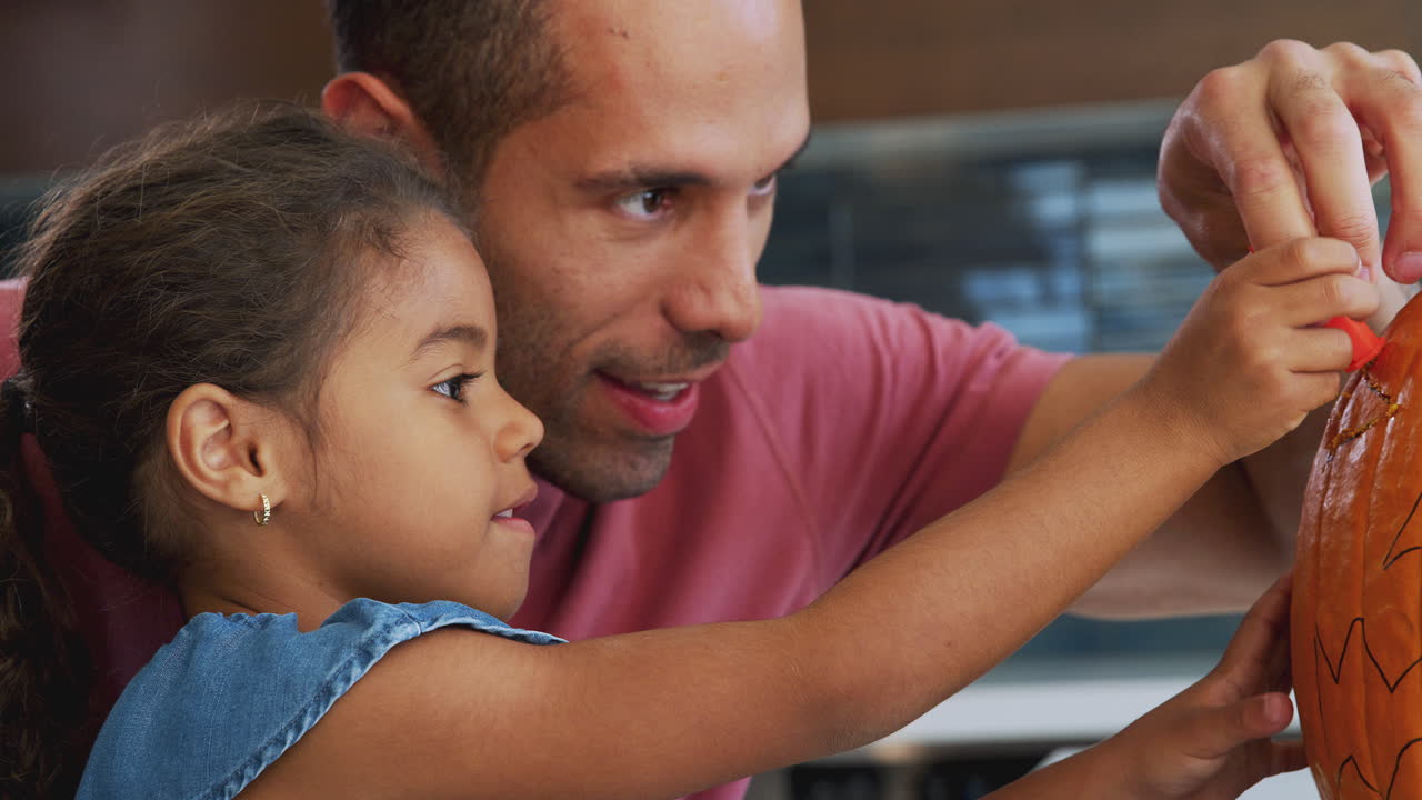 padre e hija tallando linterna de halloween de calabaza en casa