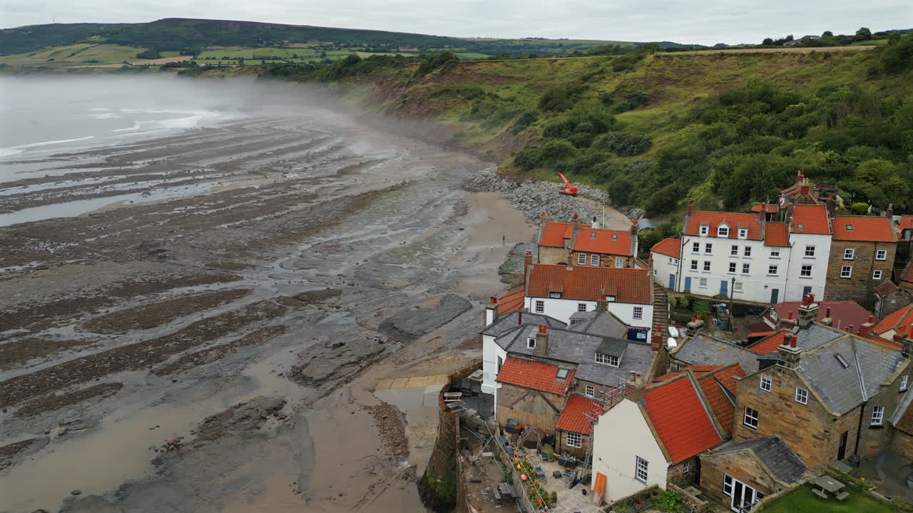 Rising Establishing Aerial Drone Shot Over Robin Hoods Bay Looking out to Sea on Misty Morning at Low Tide