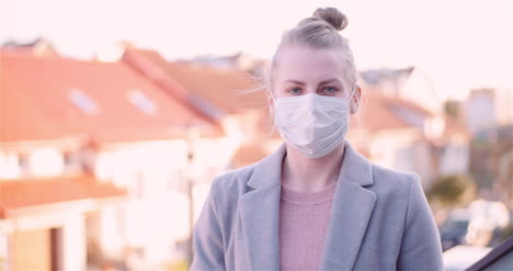 lockdown shot of woman showing thumbs up while wearing face mask at rooftop