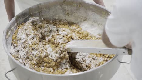 slow motion handheld shot of the mixing of a dough mass by a baker for sweets with a large mixing spoon in a sweets factory in medina sidonia