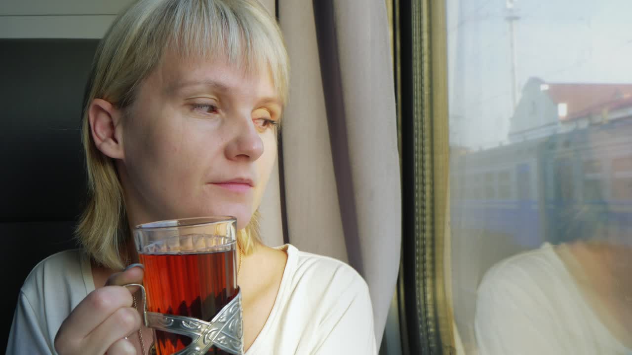 한 여성이 편안한 4k 비디오로 여행하는 기차에서 차를 마시고 있습니다.