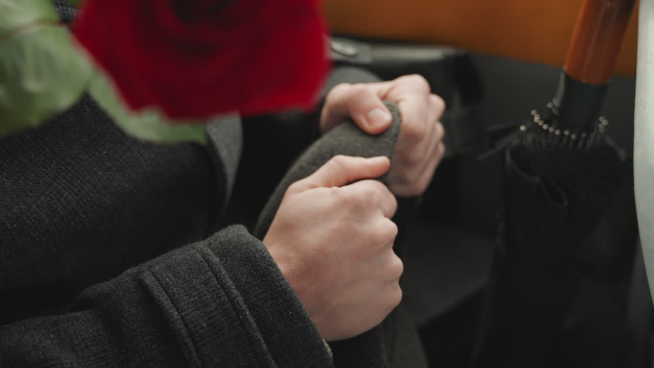 Primer plano de manos sosteniendo una rosa bajo un paraguas, manga de abrigo y mango de paraguas con agarre suave, creador ajustando el accesorio, textura suave de lana, ambiente vintage sutil, detalle táctil y romance tranquilo