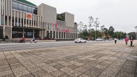 people walking, biking, and driving by a large building