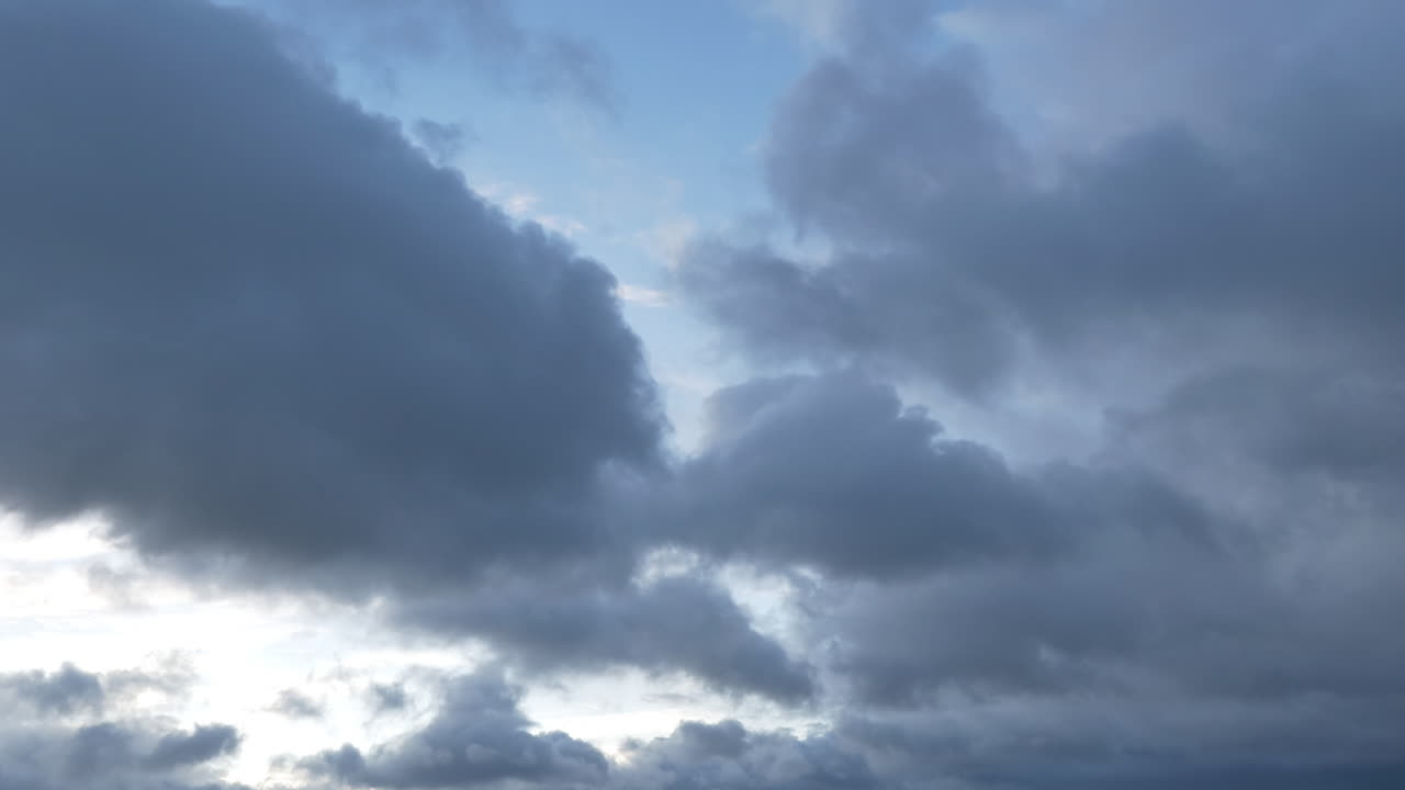 Selang waktu awan gelap dan putih bergerak melintasi langit biru. Transisi cahaya alami. Sempurna untuk latar belakang, ramalan cuaca, atau mengganti langit sinematik.