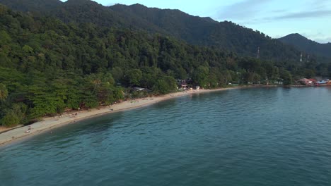 long narrow sandy beach behind jungle and mountains