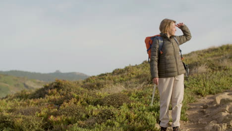 Long-shot-of-a-senior-woman-with-backpack-walking-on-mountains