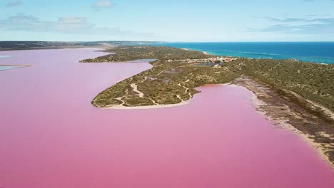 aerial wide shot, large pink water lagoon, blue ocean in background