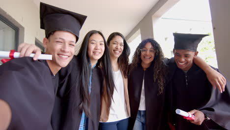 diverse group of teenagers laugh while looking at a smartphone on school stairs in high school