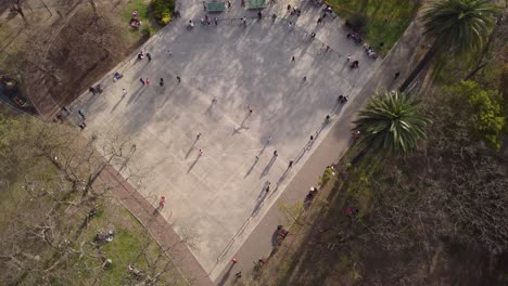 una toma aérea dinámica de arriba hacia abajo de varios patinadores jugando alrededor del parque de patinaje en forma de cuenco