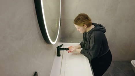 woman washing hands in modern bathroom