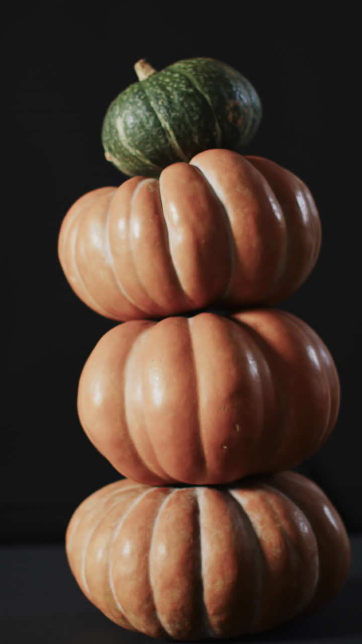 Vertical video of stack of pumpkins on black background