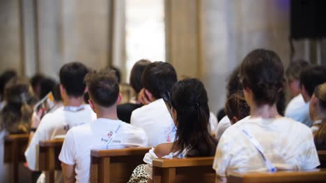people praying inside a church using fans to stay cool in warm conditions