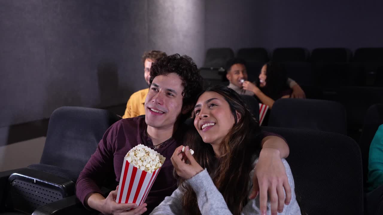 Pareja disfrutando de una película en el cine con palomitas