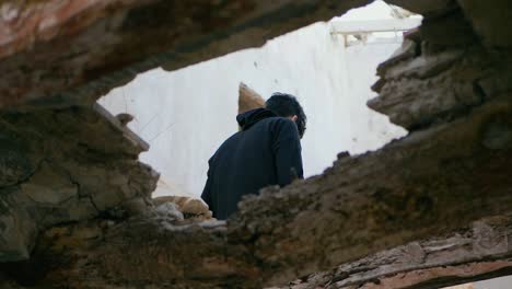 un joven, un adolescente, sentado en lo alto de una viga en una casa abandonada