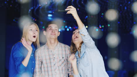 Young-People-Have-A-Good-Time-At-A-Party-Use-A-Smartphone-1