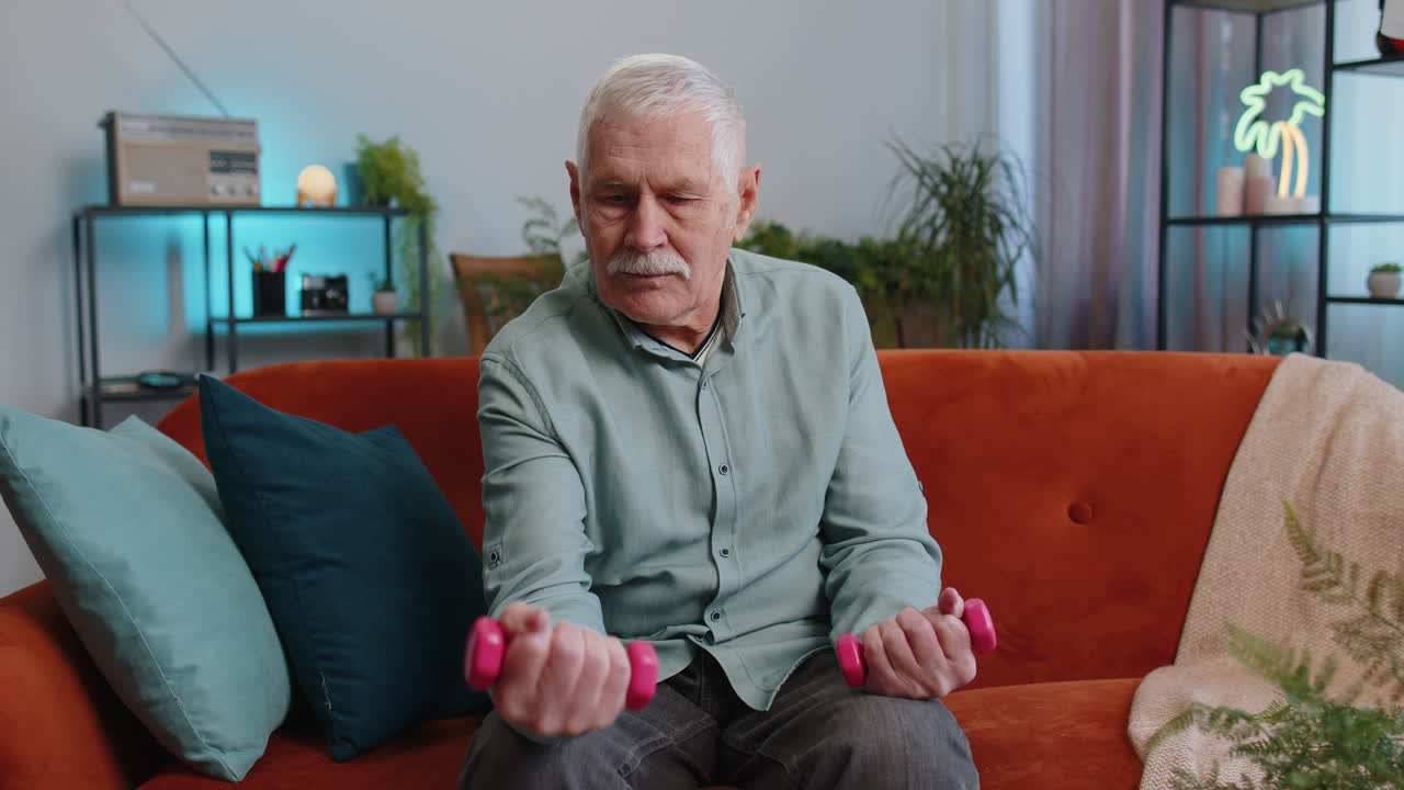Senior grandfather man doing dumbbells weight lifting fitness exercises training strength at home