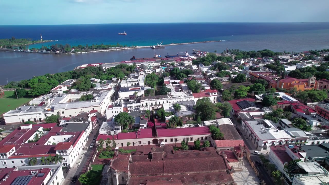 Cảnh quay flycam từ trên cao lùi lại và bay lên từ Parque Colon để lộ ra Nhà thờ Primada de America, những mái nhà của Khu Thuộc địa, Sông Ozama và Biển Caribe ở Santo Domingo.