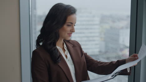 Successful-boss-reading-contract-at-office-window-close-up.-Woman-feeling-happy.