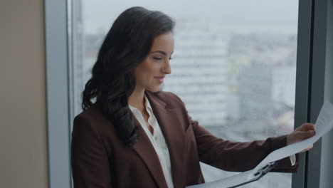 el jefe exitoso leyendo el contrato en la ventana de la oficina de cerca. la mujer se siente feliz.