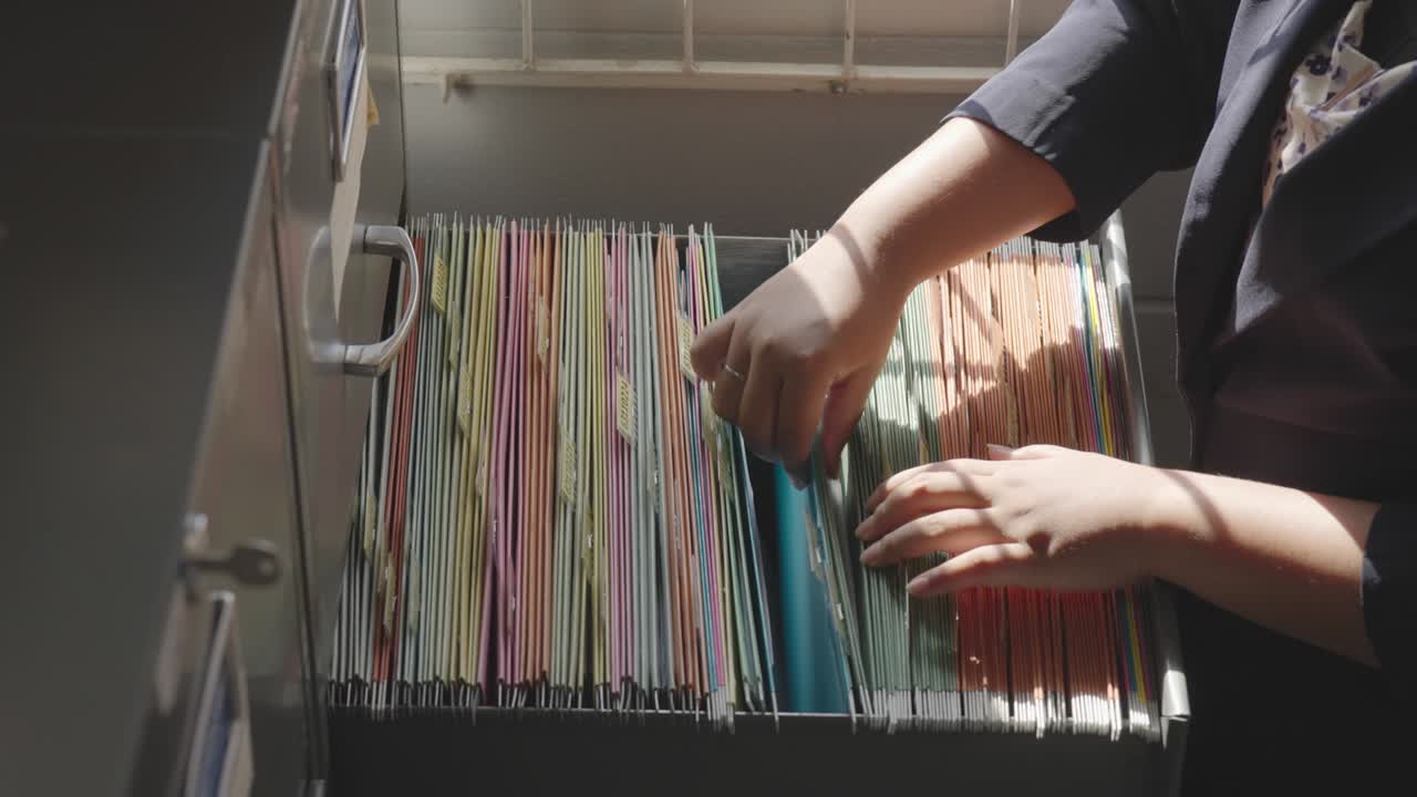 personal femenino buscando documentos en el archivo de la oficina